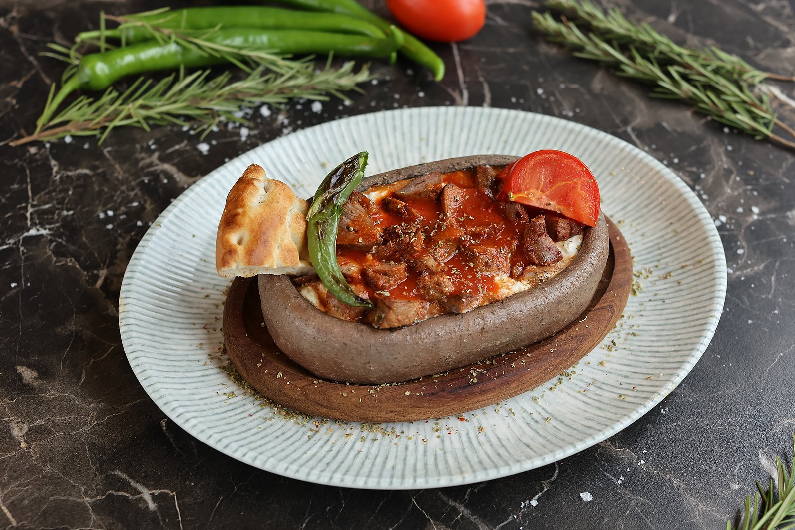 İskender-style dish with tomato sauce served in a stone bowl